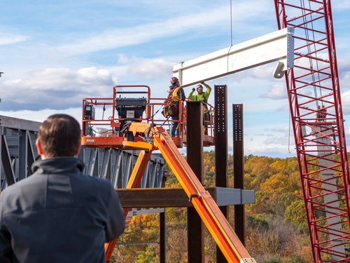 Construction workers using a crane at job site