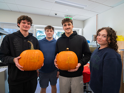 Students holding engraved pumpkins