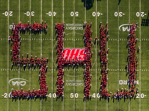 Aerial view of SHU students standing in the shape of an S H U on the football field