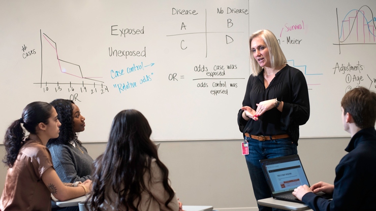 Professor talking to group of students in classroom