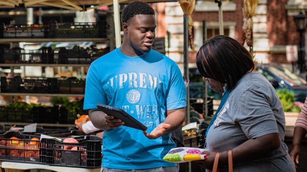 Man showing woman iPad at farmers market