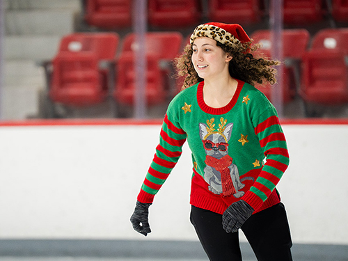 a person in a dog Christmas sweater and Santa hat ice skating