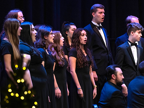 A choir performing next to a Christmas tree