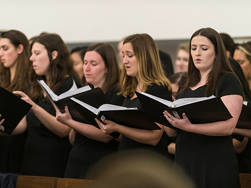 Choir members performing while looking at song books