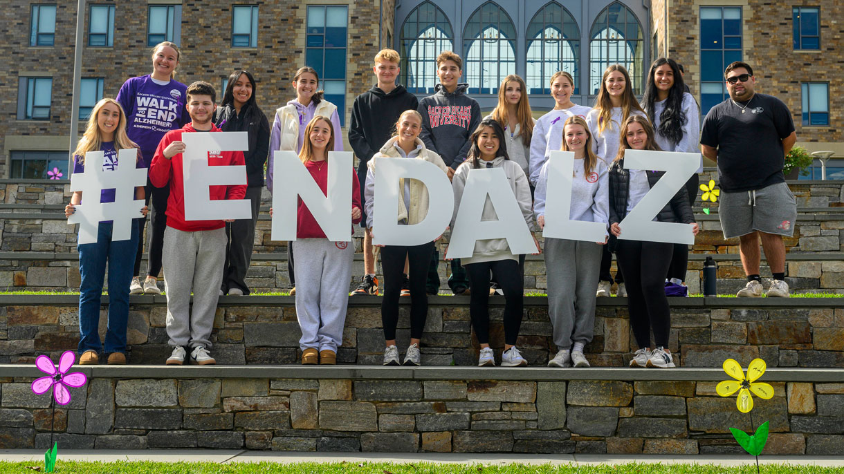 Students holding up signs that say #ENDALZ