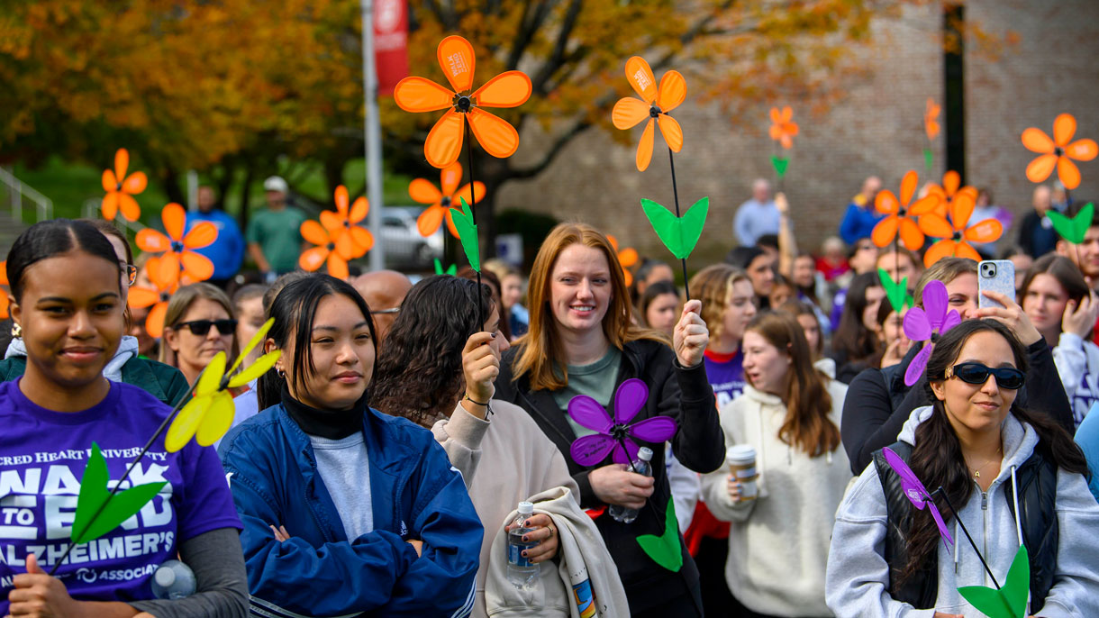 Students outside holding up pinwheel flowers at Alzheimers Walk
