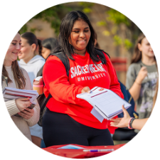 Smiling college friends handing in an interest form at an involvement fair on campus