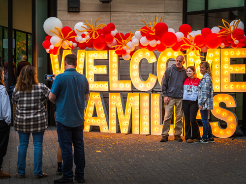 Families taking photos in front of Welcome Families lit up sign