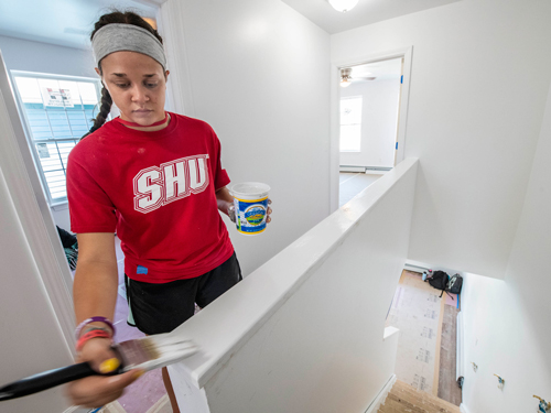 Student painting a house for Habitat for Humanity