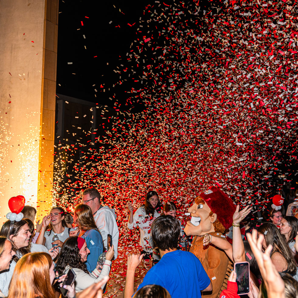 Students and Big Red dancing outside with confetti falling