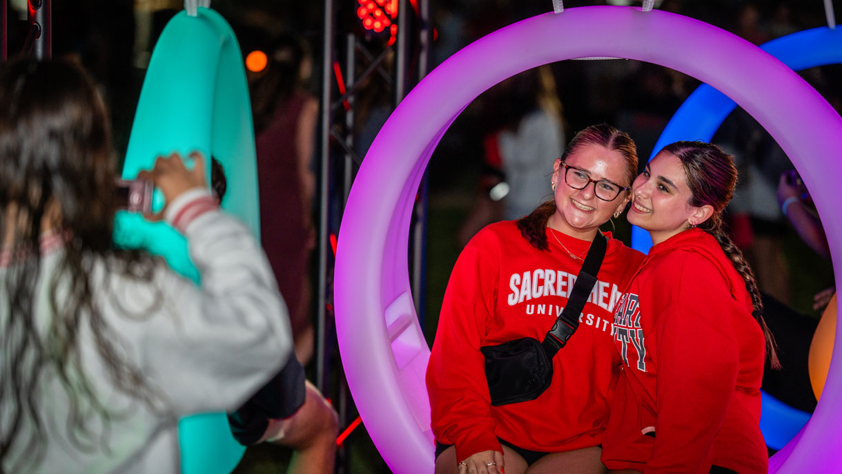 Students getting their photo taken while on a glowing swing