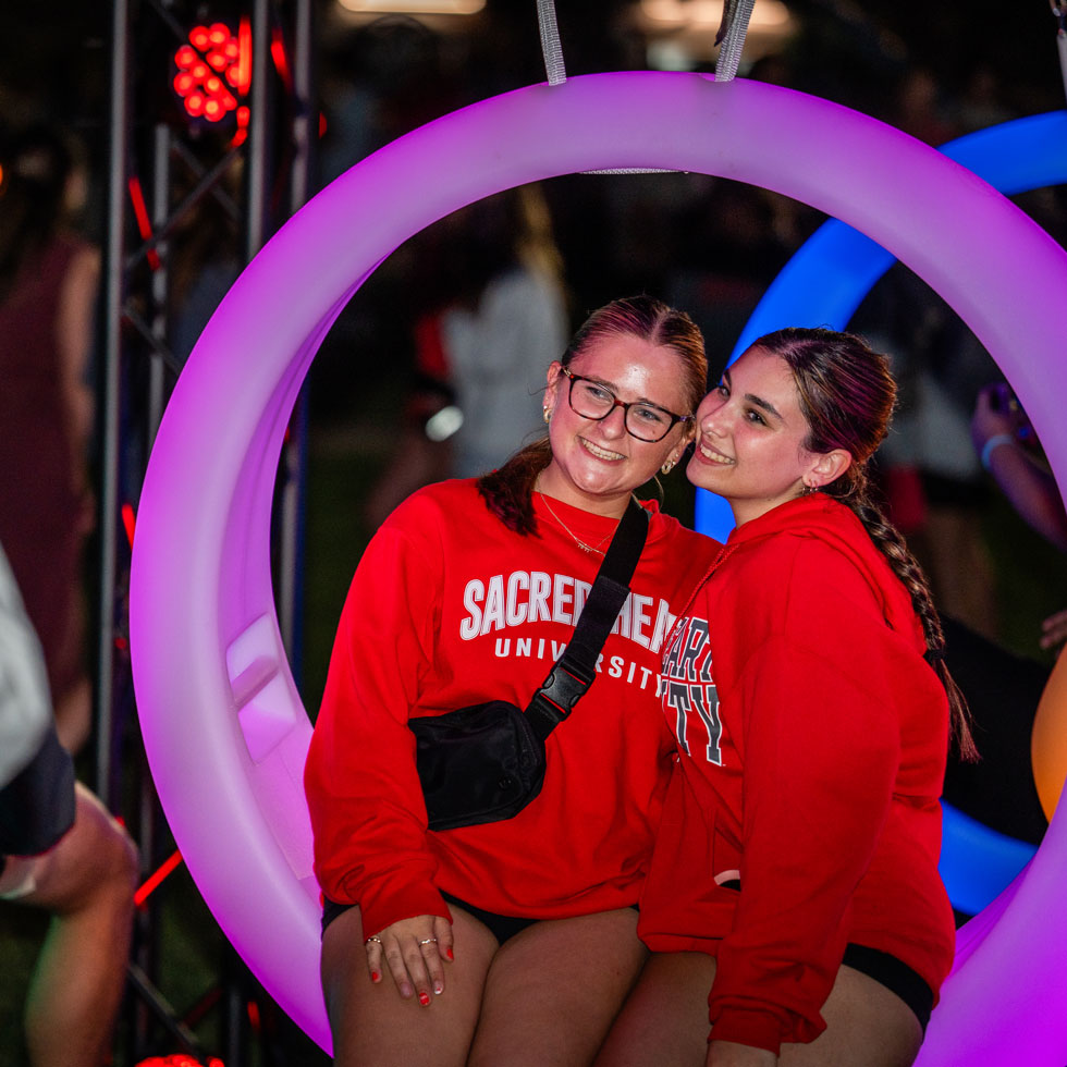 Students getting their photo taken while on a glowing swing