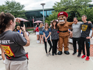 Orientation leader taking a photo of Big Red with a family