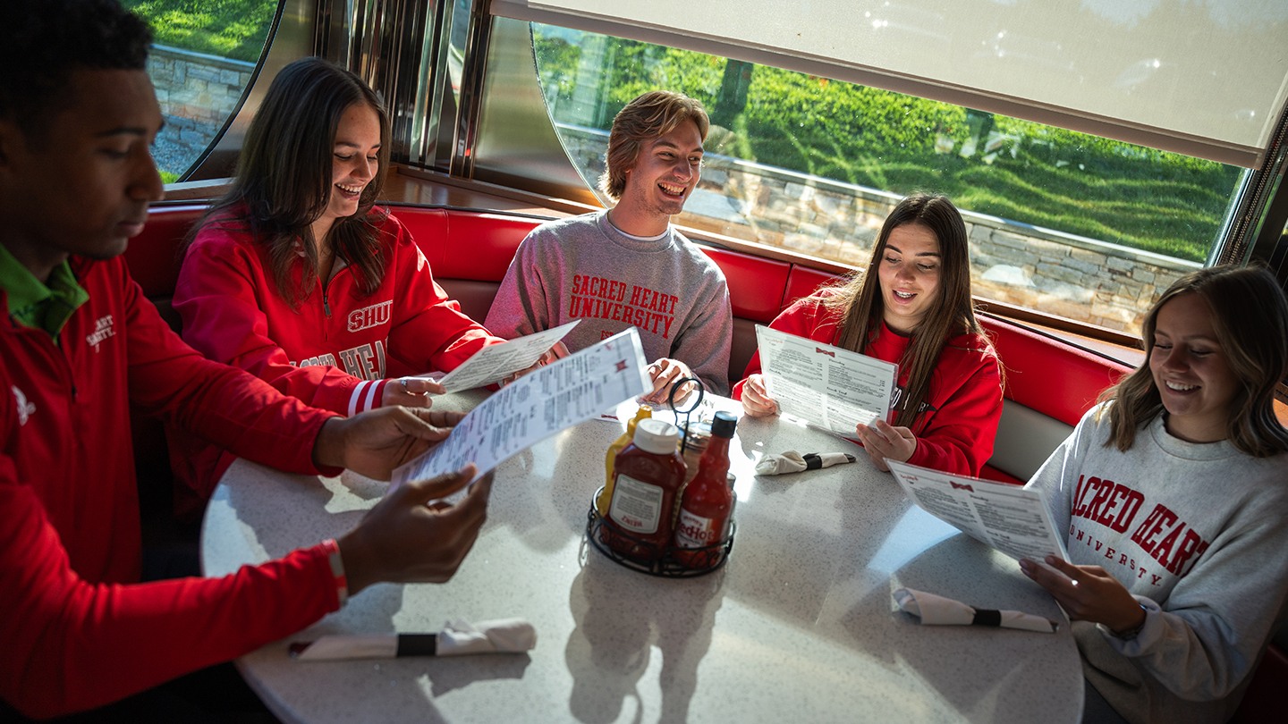 a group of friends reading menus at a diner table
