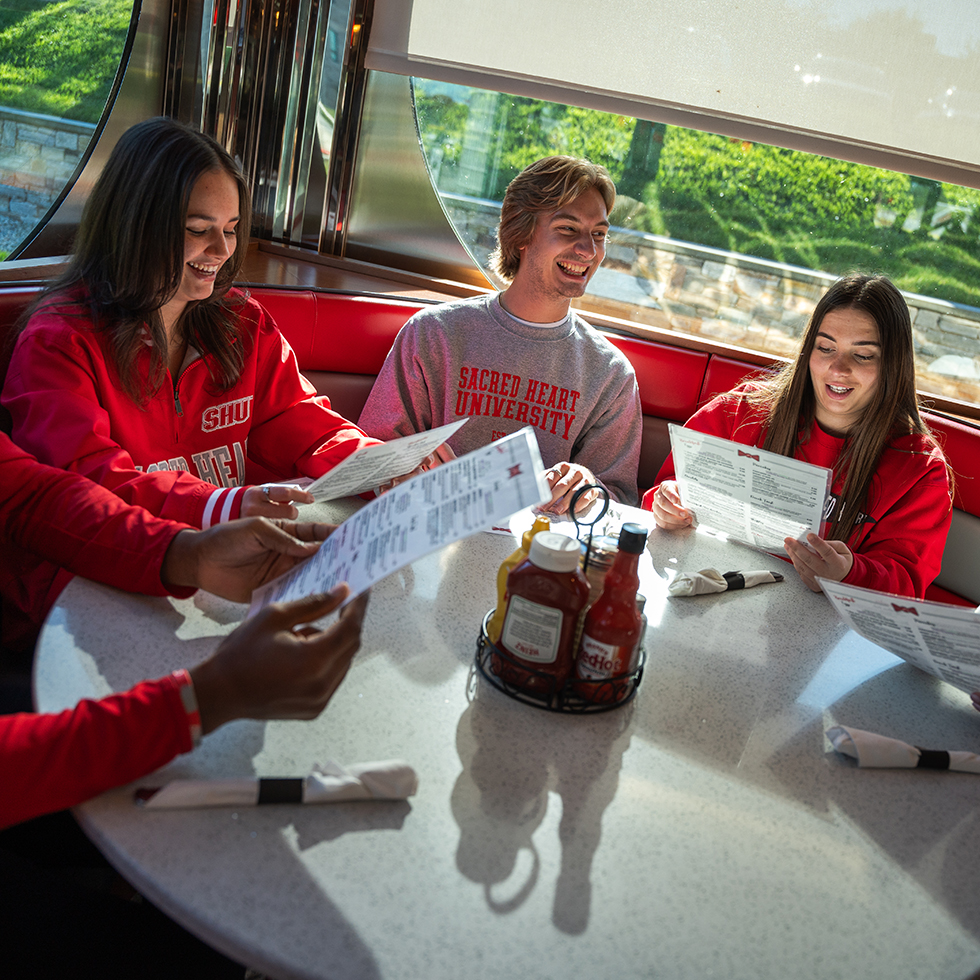 a group of friends reading menus at a diner table