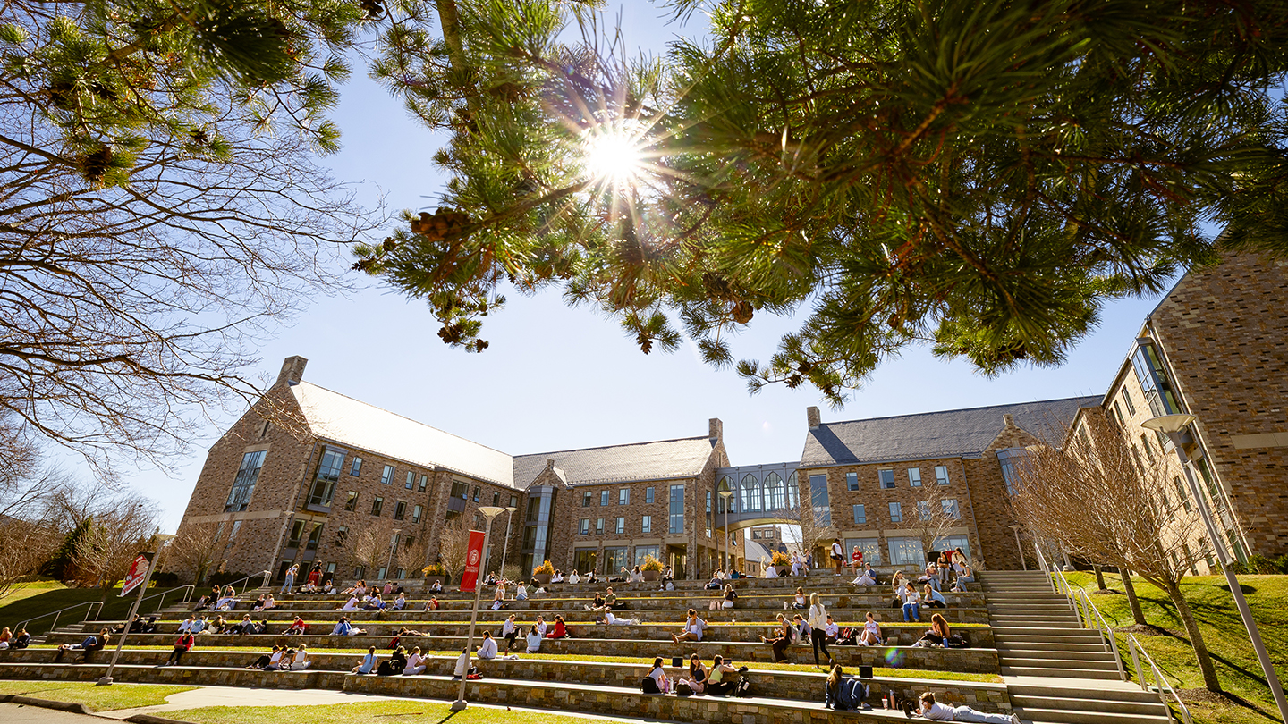 people sitting on amphitheater steps outside of stone residence halls