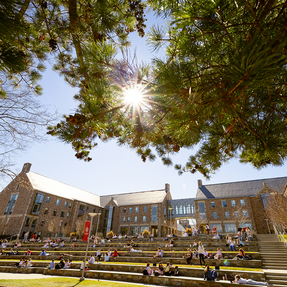 people sitting on amphitheater steps outside of stone residence halls