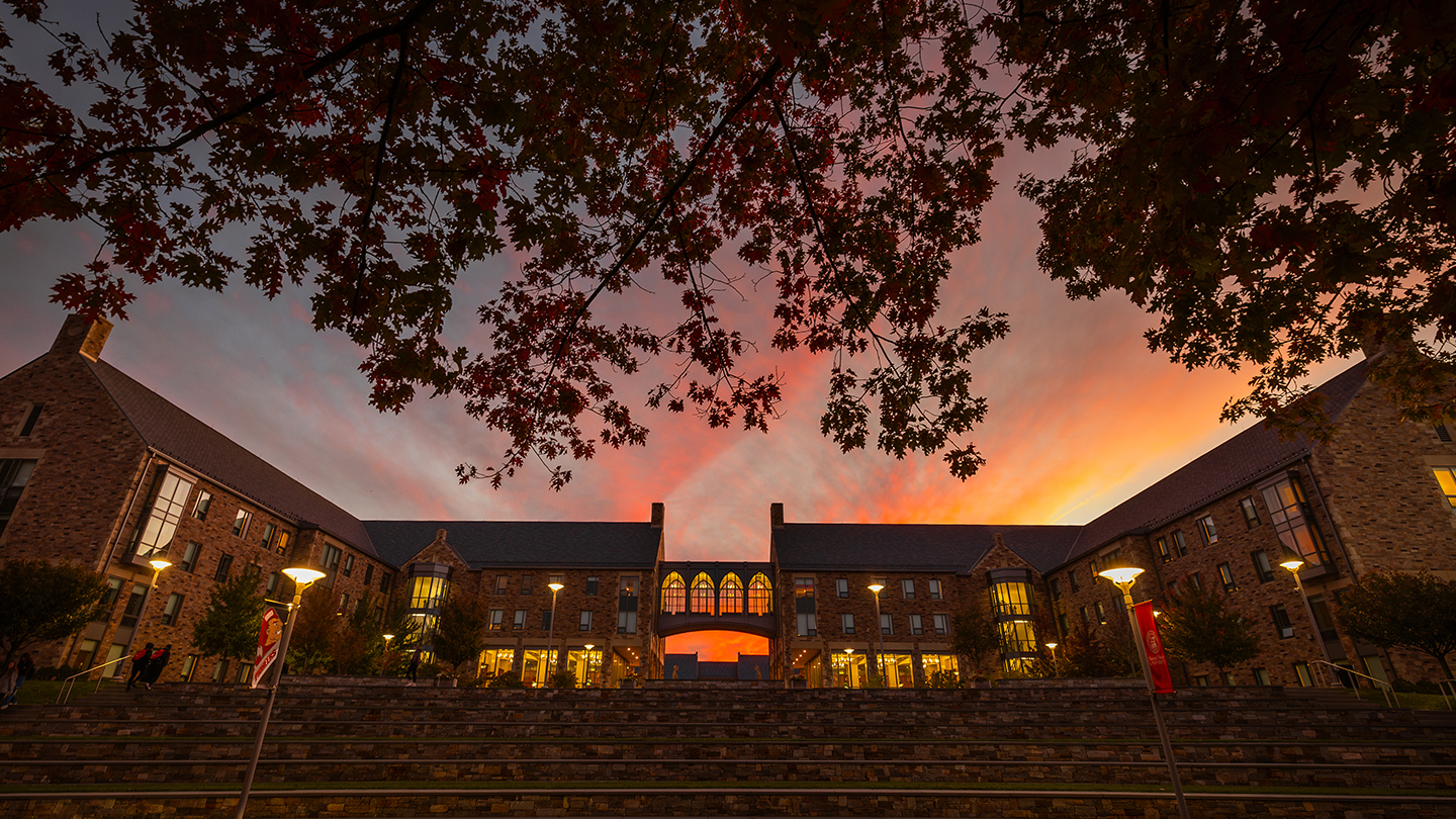 Stone residence halls silhouetted against a stunning sunset