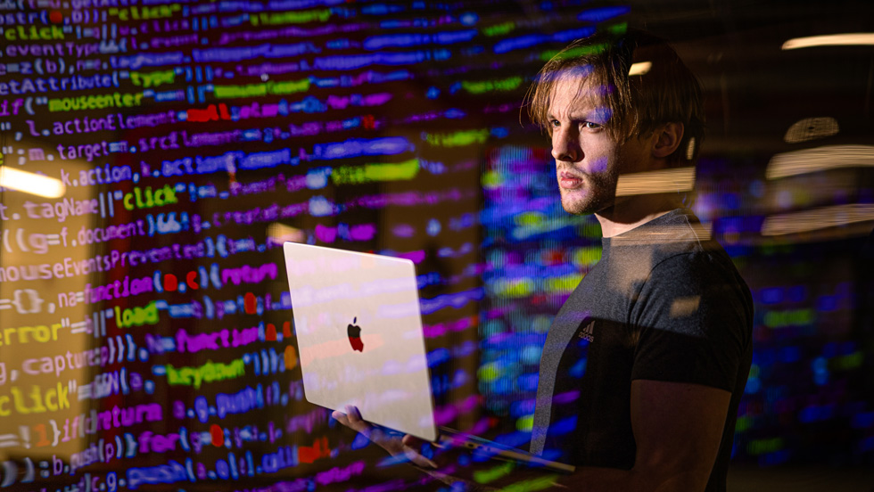 Student holding laptop with code superimposed over image