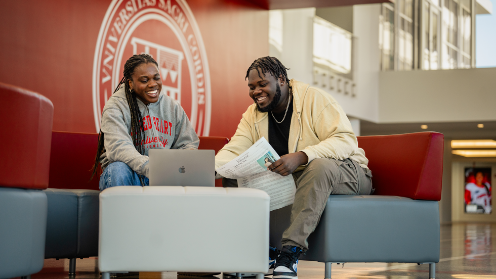 Two students working together on a laptop
