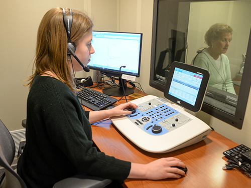 An audiologist testing the hearing of a patient with equipment