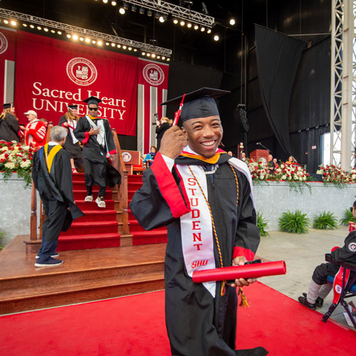 Student graduating at Commencement and holding his tassel