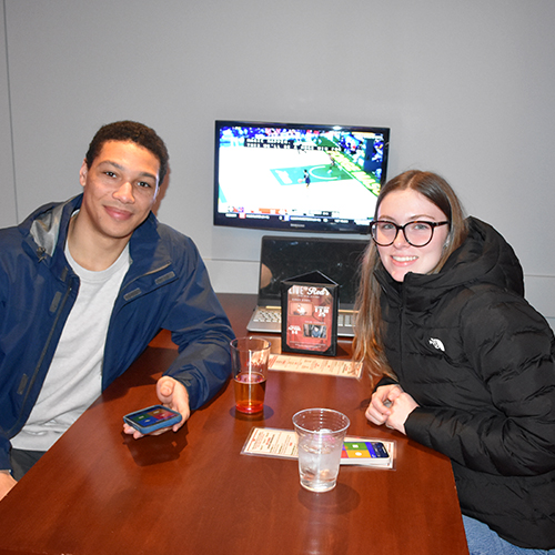 two people sitting at a table in front of a tv monitor