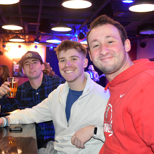 three people smiling at a bar