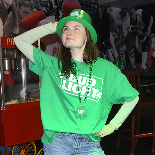 a woman wearing a green shirt and hat for St Patricks Day