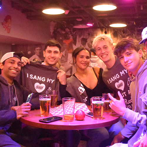 a group of five friends standing around a pub table