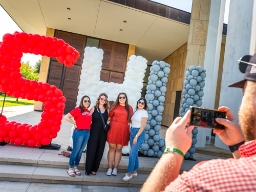 Someone taking a photo of SHU alumni in from of SHU balloons