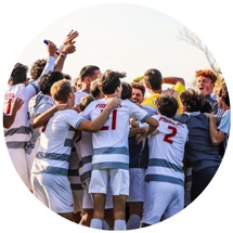 Men's soccer team huddled and celebrating