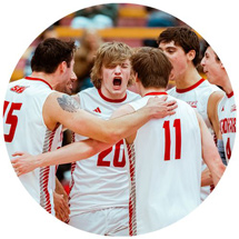 Men's volleyball team huddled and celebrating