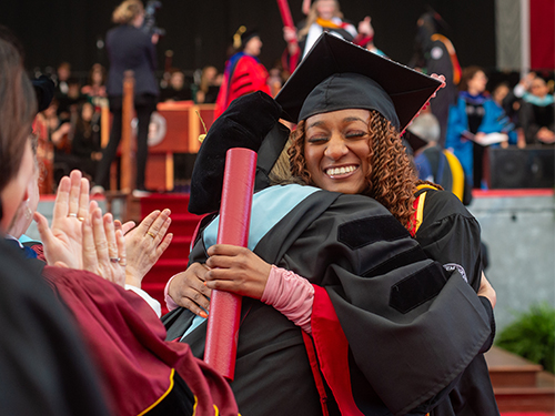 A college graduate embracing a professor at commencement