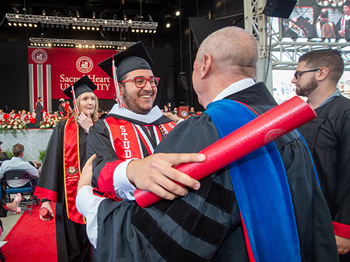 A college graduate embracing a professor at commencement