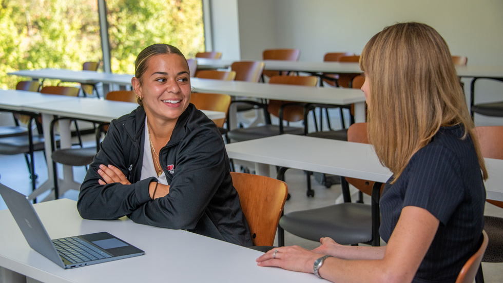 Student talking to professor in classroom