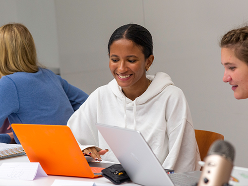 To people looking at a laptop computer and smiling